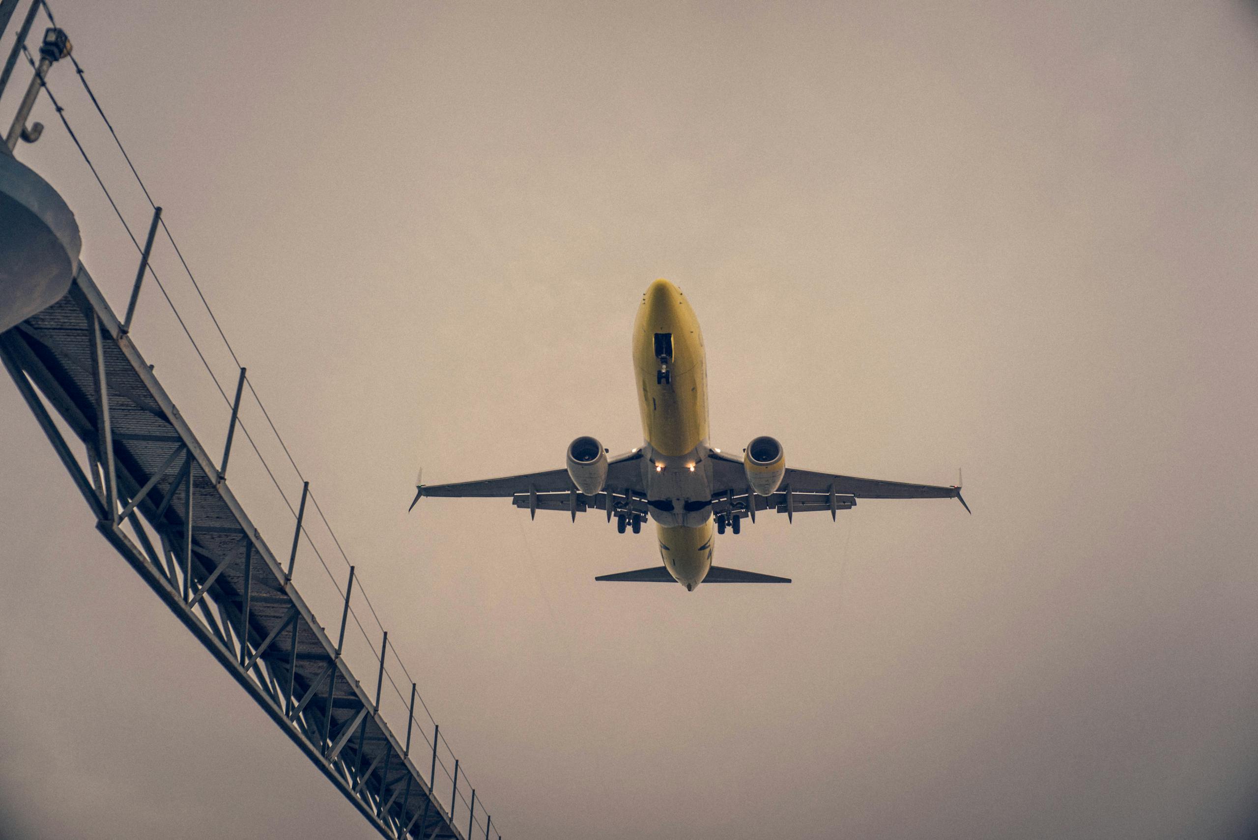 A striking view of a yellow airplane landing against a cloudy sky in Teguise, Spain.
